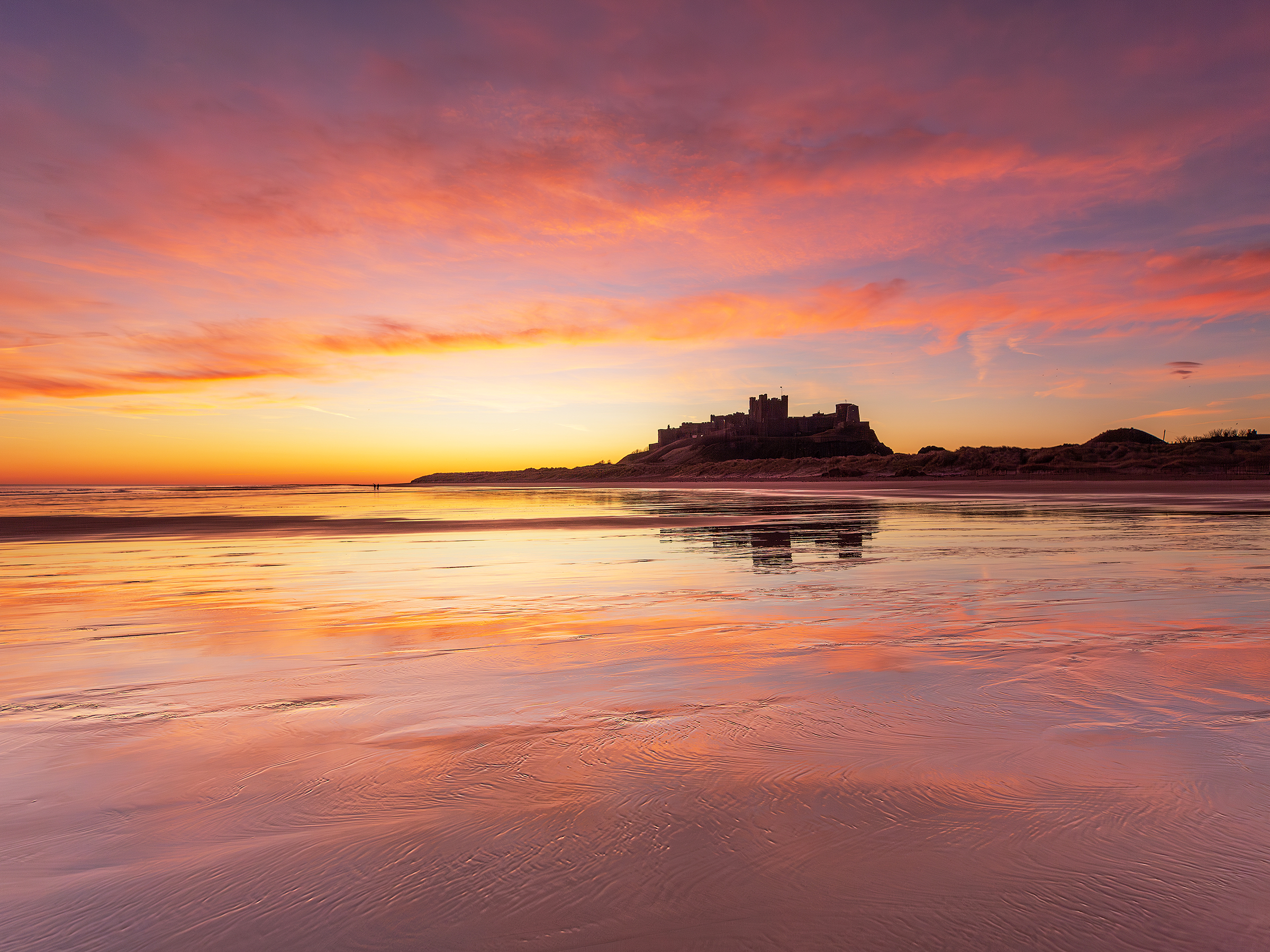 Sunrise over a quiet North East beach with a distant lighthouse